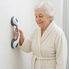 White and gray no-drill bathroom grab bar mounted on a tiled shower wall