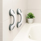 White and gray no-drill bathroom grab bar mounted on a tiled shower wall