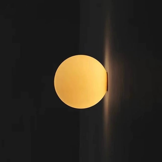 Modern frosted glass globe LED wall sconce mounted on a wall