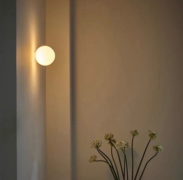 Modern frosted glass globe LED wall sconce mounted on a wall