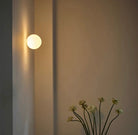 Modern frosted glass globe LED wall sconce mounted on a wall