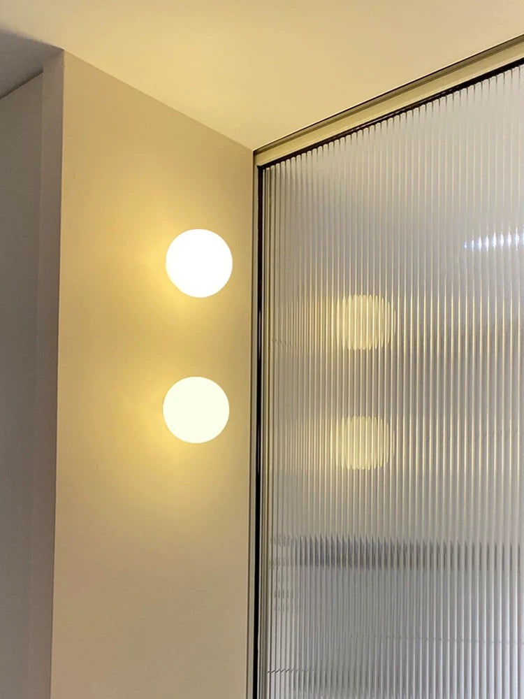 Modern frosted glass globe LED wall sconce mounted on a wall