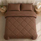 Quilted comforter with geometric diamond stitching on a bed